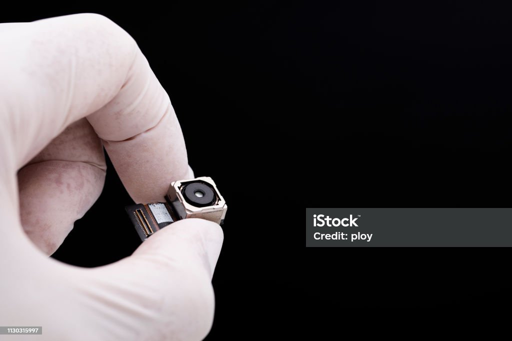 Small spy camera in hand concept on black background