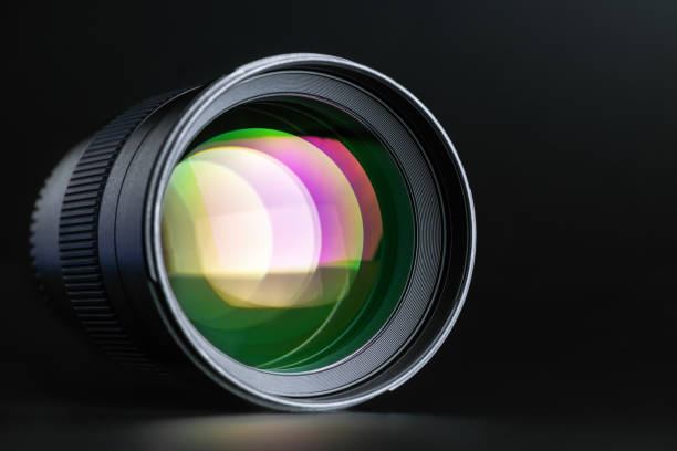 Das Kameraobjektiv mit mehrfarbiger Beleuchtung auf schwarzem Hintergrund. Optik. Makro-Horizontalfoto